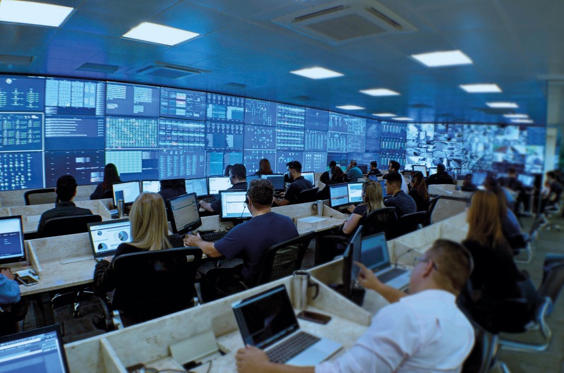 Equipe acompanhando painéis em uma central de monitoramento